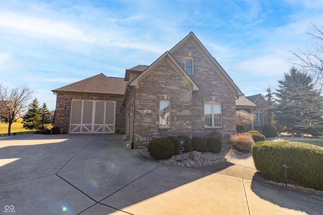 view of front of house featuring a garage, brick siding, roof with shingles, and driveway