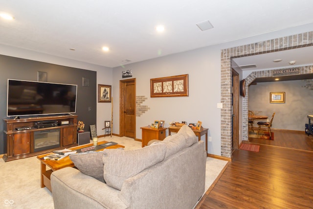 living room featuring a glass covered fireplace, recessed lighting, wood finished floors, and baseboards