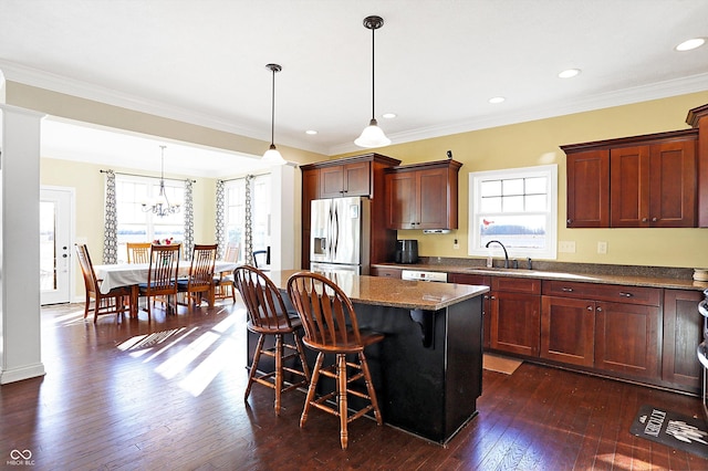 kitchen with stainless steel refrigerator with ice dispenser, a sink, a kitchen breakfast bar, dark wood finished floors, and a center island