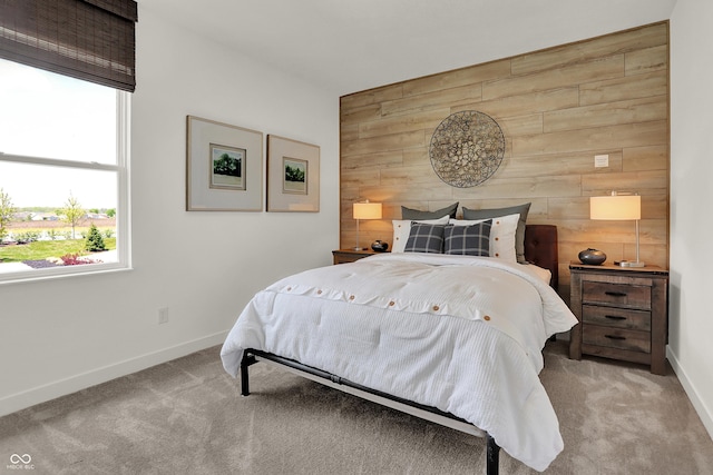 carpeted bedroom with baseboards, wood walls, and an accent wall