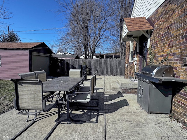 view of patio with outdoor dining area, an outbuilding, and fence