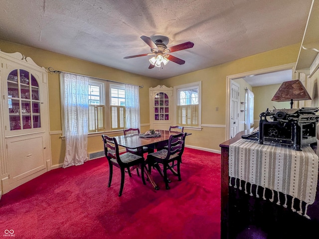 carpeted dining room featuring baseboards, a ceiling fan, visible vents, and a textured ceiling