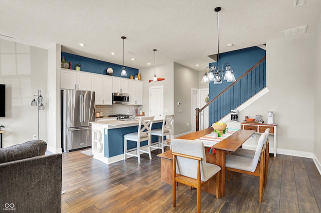 dining room featuring visible vents, dark wood-style floors, an inviting chandelier, baseboards, and stairs