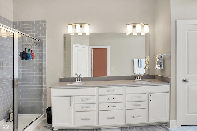 full bath with double vanity, a shower stall, marble finish floor, and a sink