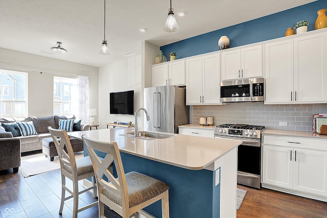 kitchen featuring a sink, decorative backsplash, dark wood-type flooring, appliances with stainless steel finishes, and open floor plan