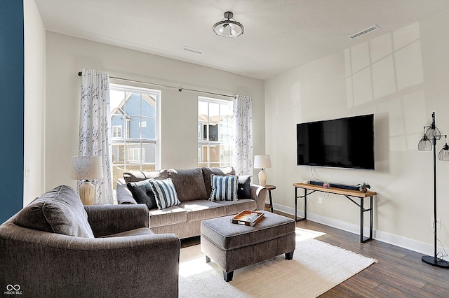 living area with wood finished floors, visible vents, and baseboards