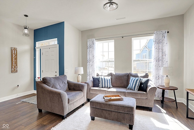 living room with wood finished floors, visible vents, and baseboards