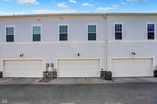 back of house with a garage and central AC