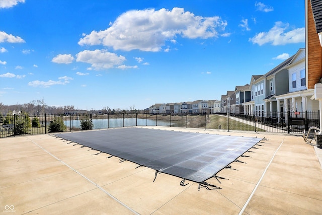 view of swimming pool featuring a residential view, a water view, and fence