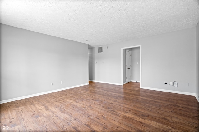 spare room with visible vents, baseboards, a textured ceiling, and dark wood-style floors