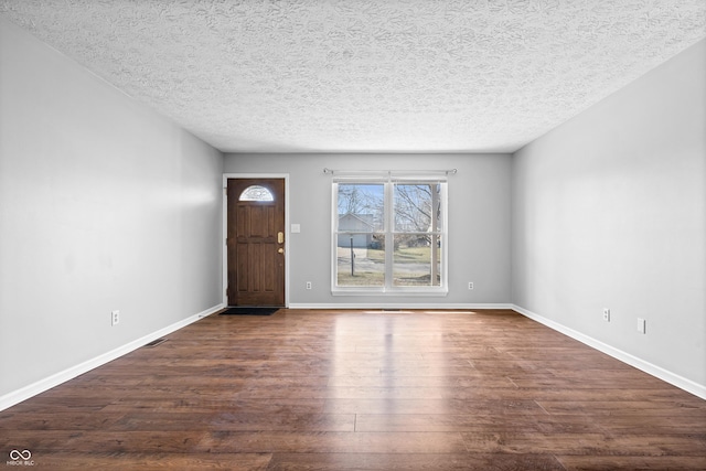 foyer entrance with baseboards, a textured ceiling, and dark wood finished floors