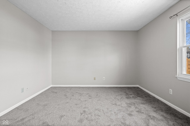 carpeted spare room featuring a textured ceiling and baseboards