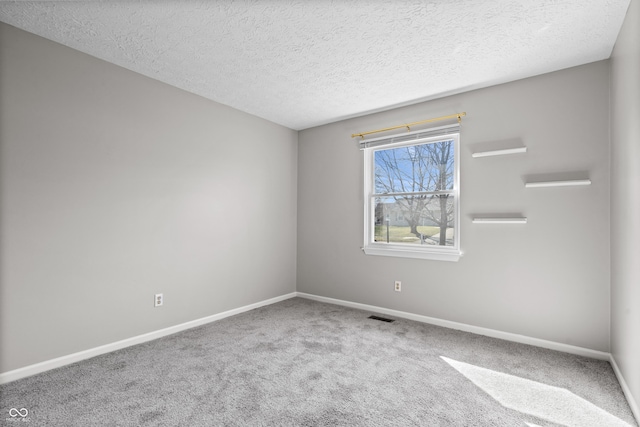 carpeted spare room with visible vents, a textured ceiling, and baseboards