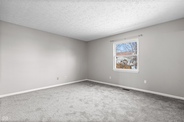 unfurnished room featuring baseboards, carpet floors, a textured ceiling, and visible vents