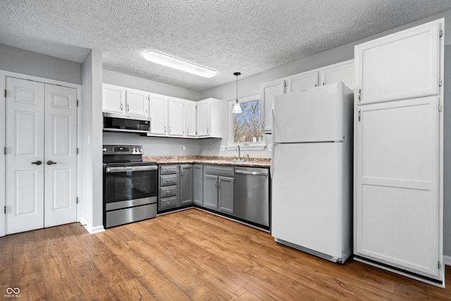 kitchen featuring white cabinets, gray cabinetry, stainless steel appliances, and light wood-style floors