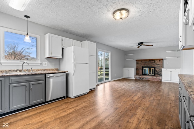 kitchen featuring gray cabinetry, stainless steel dishwasher, wood finished floors, freestanding refrigerator, and ceiling fan