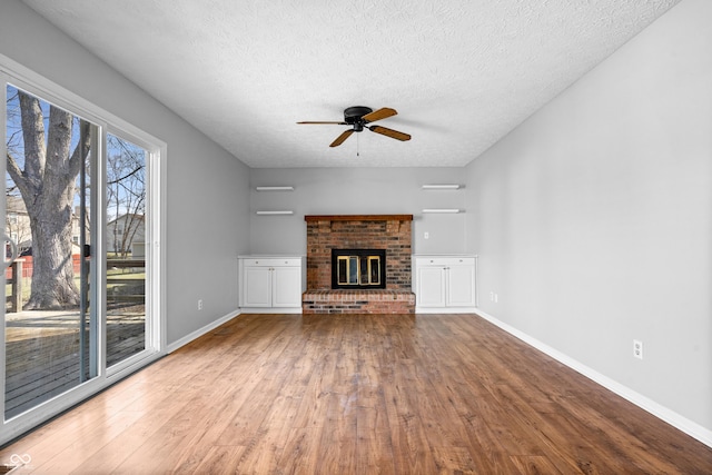 unfurnished living room with a textured ceiling, wood finished floors, baseboards, and ceiling fan