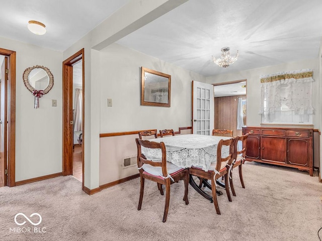 dining area featuring visible vents, light colored carpet, an inviting chandelier, and baseboards