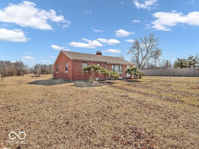 view of front facade featuring fence, brick siding, and a chimney