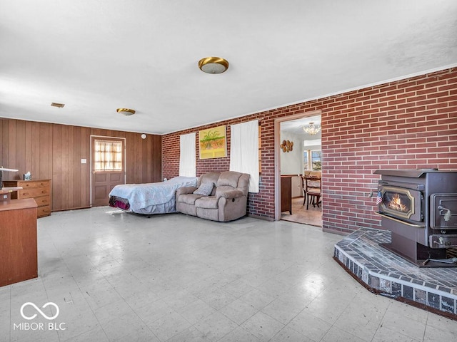 living room with tile patterned floors, brick wall, and a wood stove