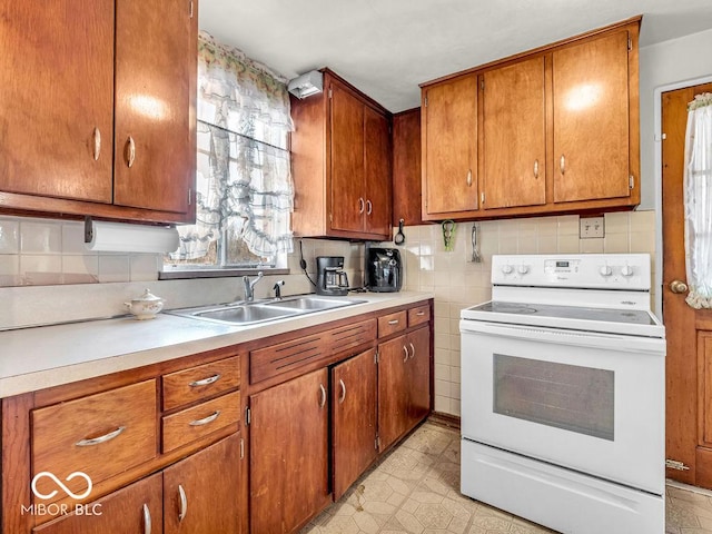 kitchen with light floors, light countertops, white electric range oven, brown cabinetry, and a sink