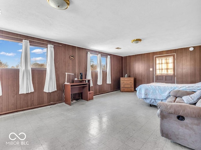 bedroom with tile patterned floors, multiple windows, and wood walls