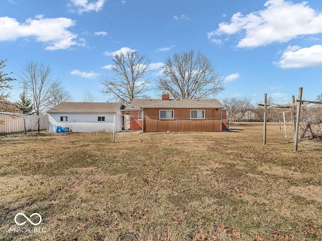 back of house featuring a chimney, a yard, and fence