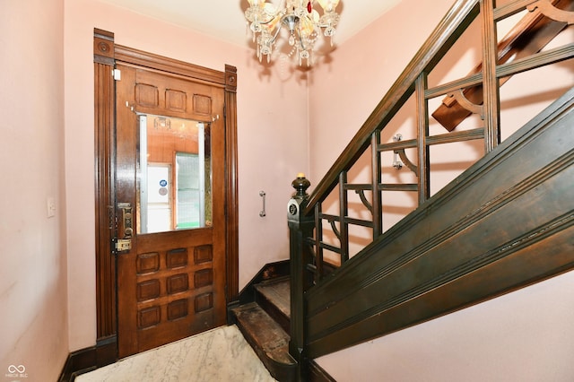 foyer with baseboards, stairs, and an inviting chandelier