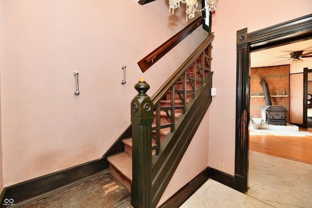 staircase featuring baseboards and a wood stove