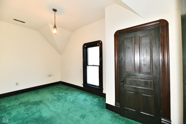 interior space featuring vaulted ceiling, baseboards, visible vents, and dark carpet