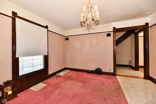 carpeted spare room featuring a chandelier, visible vents, and a barn door