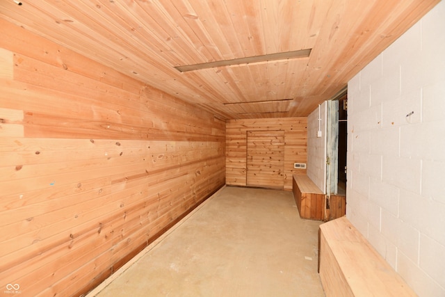 corridor with wooden walls, wood ceiling, and concrete flooring