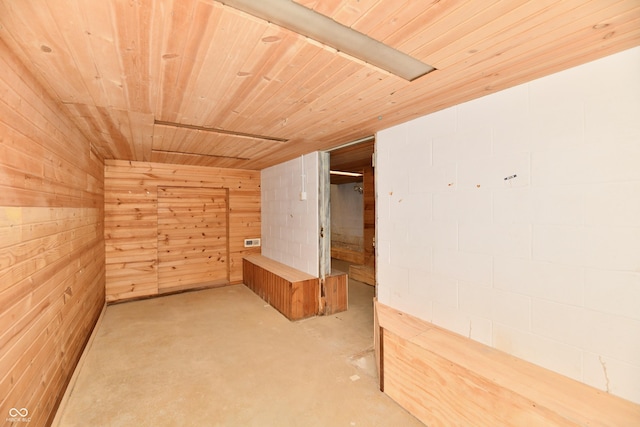 bonus room featuring concrete flooring, wooden ceiling, and wood walls