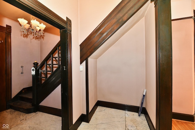 stairs featuring baseboards, marble finish floor, and an inviting chandelier