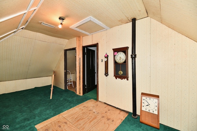 additional living space with wallpapered walls, attic access, visible vents, and vaulted ceiling