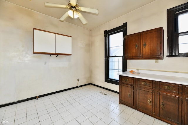 kitchen featuring baseboards, ceiling fan, and light countertops