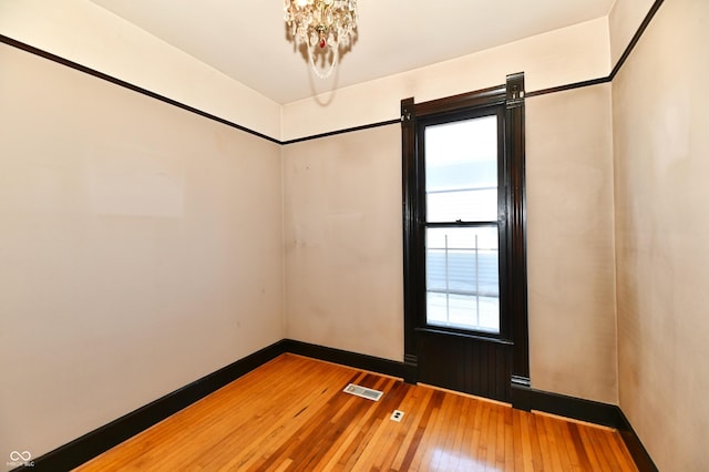 unfurnished room featuring hardwood / wood-style floors, baseboards, and visible vents