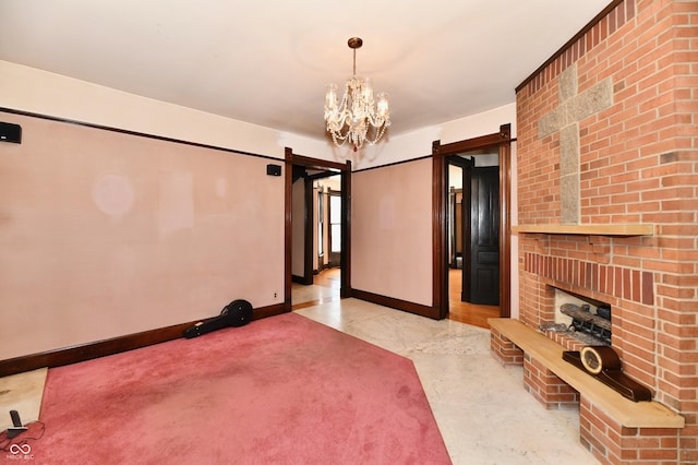 interior space with a barn door, a notable chandelier, a brick fireplace, and baseboards