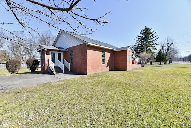 view of home's exterior featuring brick siding, a lawn, and entry steps