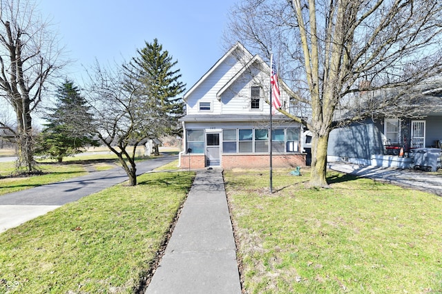 view of front of home with brick siding, a front lawn, and a sunroom