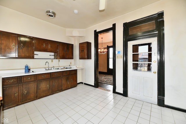 kitchen featuring a sink, dark brown cabinetry, an inviting chandelier, light countertops, and light tile patterned floors