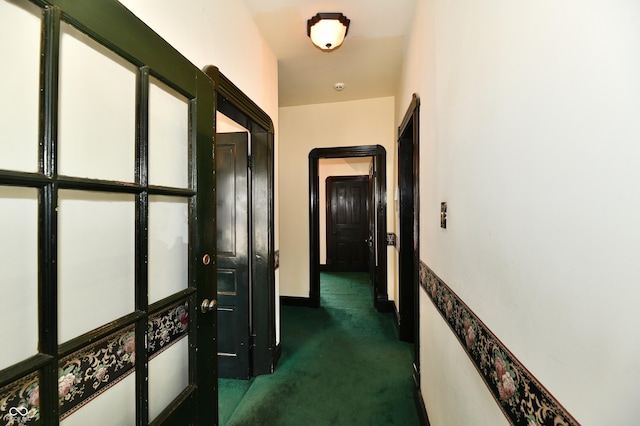 corridor with dark colored carpet and baseboards