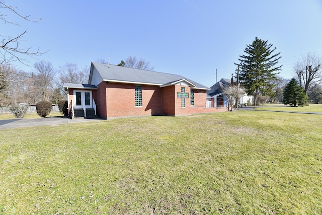 view of home's exterior featuring french doors, brick siding, and a lawn