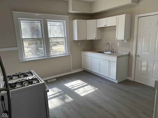 kitchen featuring visible vents, a sink, wood finished floors, white cabinetry, and white range with gas stovetop