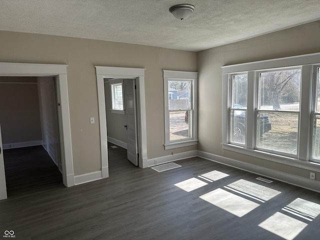 unfurnished bedroom with visible vents, baseboards, a textured ceiling, and dark wood-style flooring