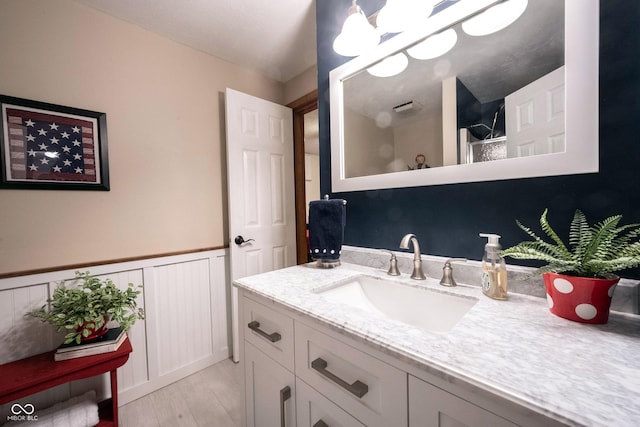 bathroom featuring vanity, wood finished floors, and wainscoting