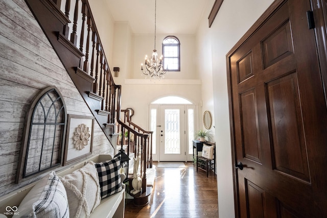 entryway with a notable chandelier, stairs, a towering ceiling, and dark wood-style flooring