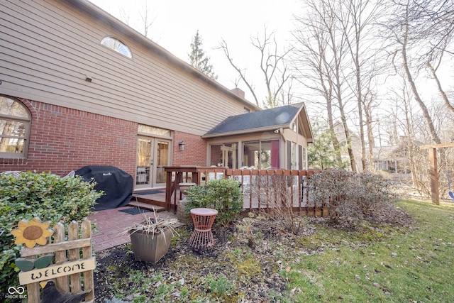 rear view of property with brick siding, french doors, a chimney, and a deck