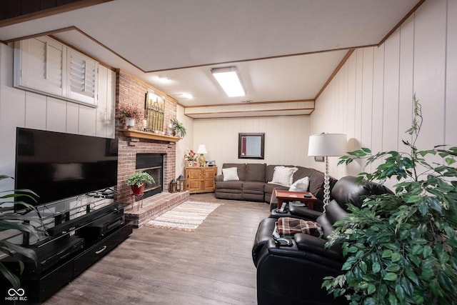 living area featuring wood finished floors, a fireplace, and crown molding