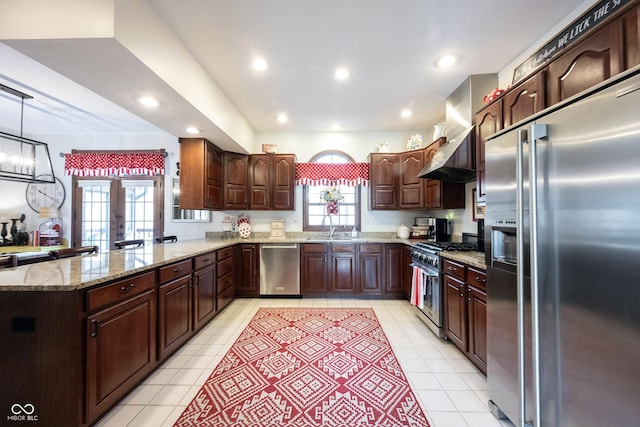 kitchen with premium appliances, a healthy amount of sunlight, wall chimney range hood, and a sink